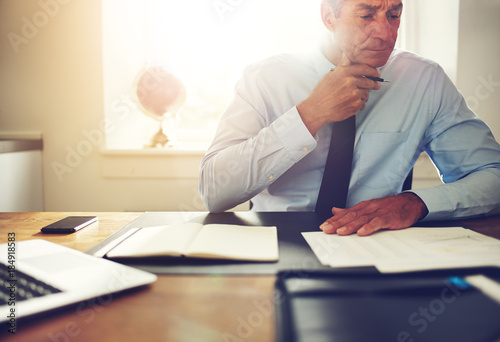 Mature executive reading paperwork at a desk in an office