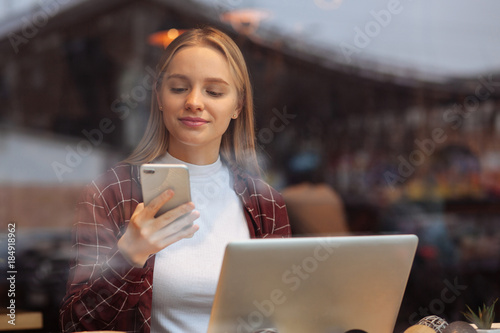 Positive delighted student looking at her telephone