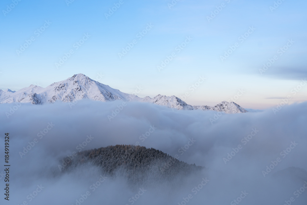 Mountains in winter emerge from the fog