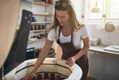 Photography Artisan working by a kiln in her creative pottery studio