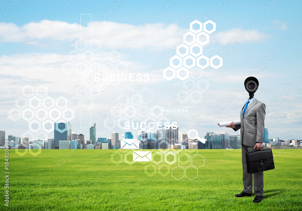 Camera headed man standing on green grass against modern cityscape Camera headed man standing on green grass against modern cityscape