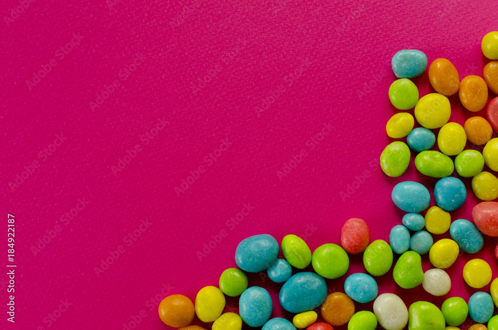 Obraz premium Multicolored candy on pink background with space for text