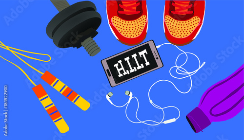 Fitness, healthy and active lifestyles concept. Dumbbells, sport shoes, smart phone with earphone and water bottle with word HIIT (high intensity interval training)