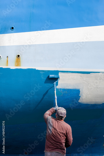 Un homme peint la coque d’un bateau