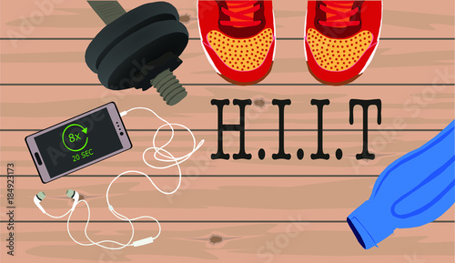 Fitness, healthy and active lifestyles concept. Dumbbells, sport shoes, smart phone with earphone and water bottle on wooden gym floor with word HIIT (high intensity interval training)