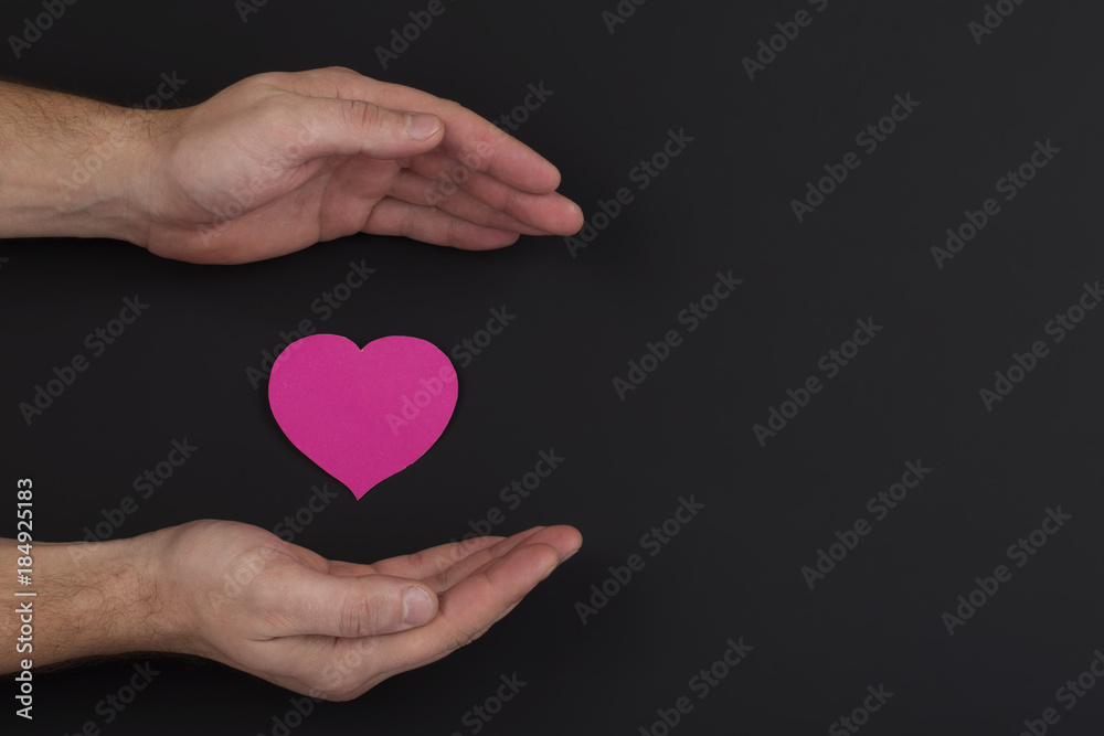 Heart in a palm on dark background with copy space Heart in a palm on dark background with copy space