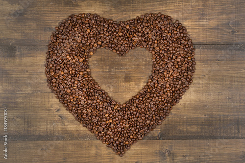 Heart of coffee beans on a wooden surface © Denis