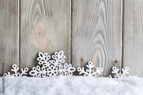 Christmas background - snowflakes on snow and wooden wall
