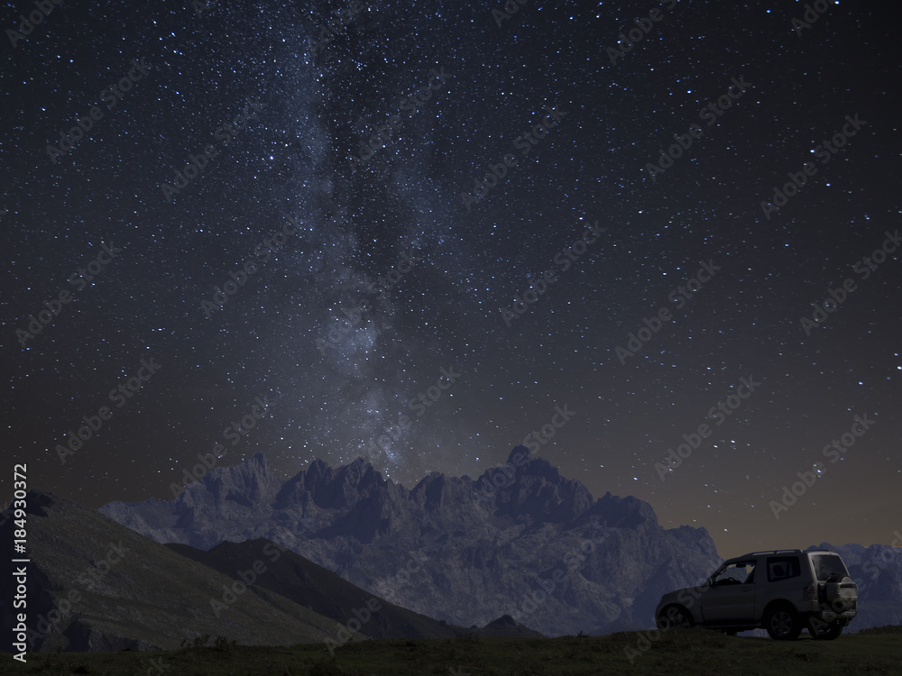 4x4 offroad Car under mountains and milky way at night, adventure concept