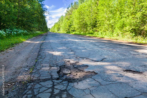 Fotografie Dangerous pothole in the asphalt rural road. Road damage