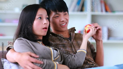 happy young asian couple watching TV in home