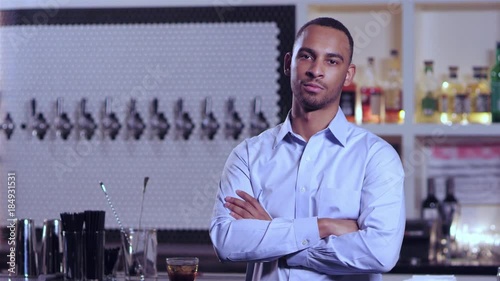 Portrait shot of a young attractive African American man smiling with his arms crossed at a bar