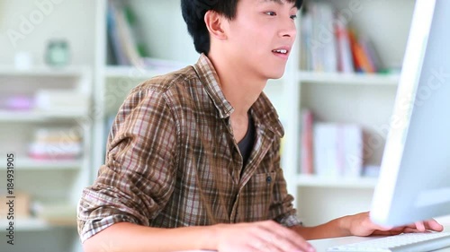 young asian man using computer indoor