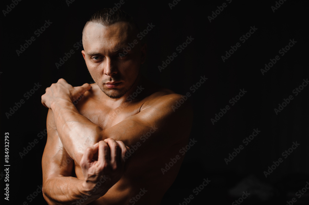 Muscular sexy and tanned bodybuilder posing in studio