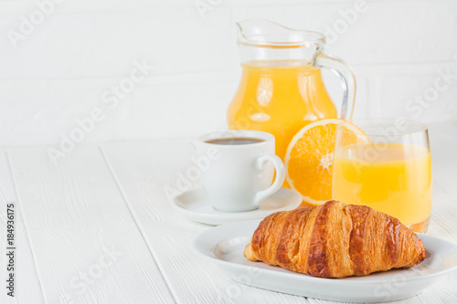 Freshly baked croissant, orange juice, fresh fruits, jam on white wooden background. French breakfast. Fresh pastries for morning. Delicious dessert. Closeup photography. Horizontal banner
