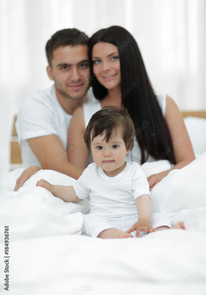 Portrait of a joyful family sitting on the bed at home