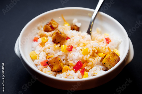 vegetarian rice salad with tofu and brown rice on black background.