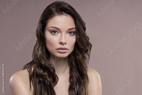 Young and healthy woman with light make-up on beige background.