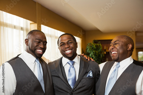 Groom and groomsmen smiling at a wedding.