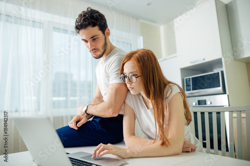 Foto Unhappy couple unable to pay loan on time: couple sitting at table with laptop