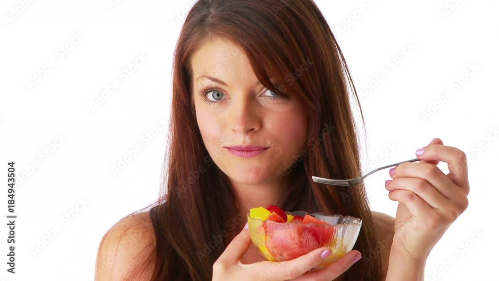 Sexy young woman eating fruit from a bowl
