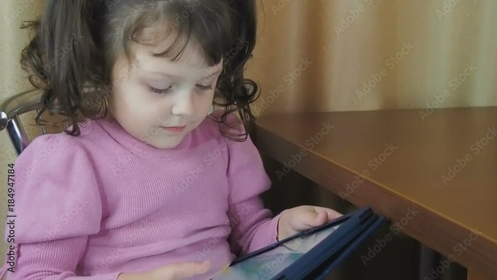 Child with a tablet. Beautiful little girl is playing on the tablet. Child with a tablet. Beautiful little girl is playing on the tablet.