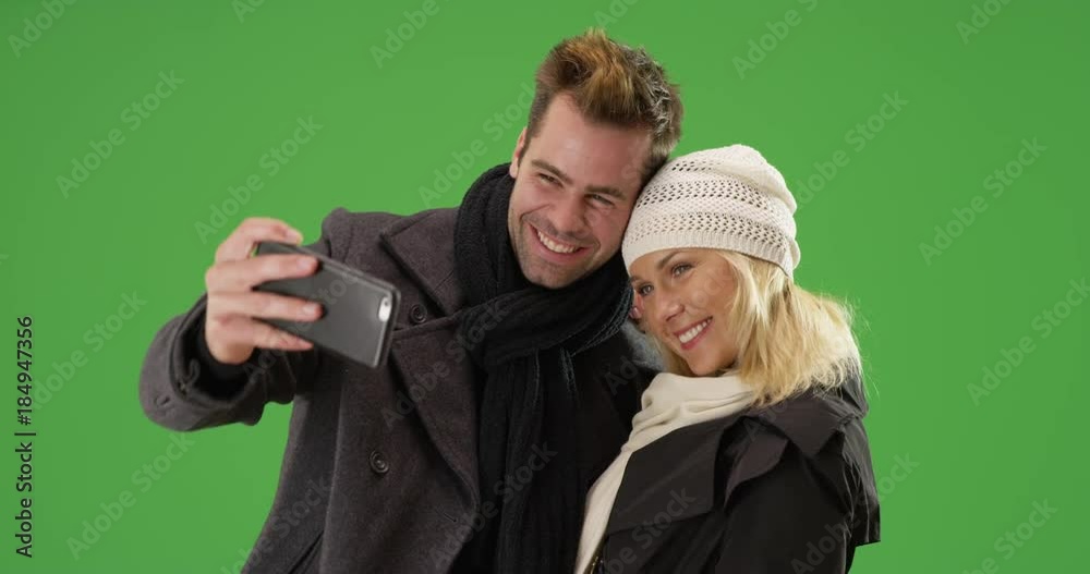 Happy yuccie couple taking selfies during winter time on green screen. On green screen to be keyed or composited. Happy yuccie couple taking selfies during winter time on green screen. On green screen to be keyed or composited.