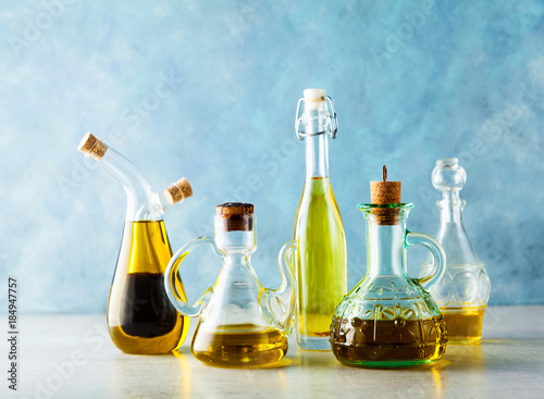 different shapes, types and sizes of cruets with olive oil on the table on blue photo