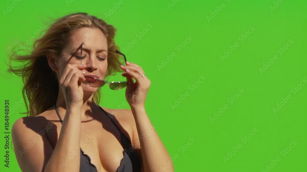 Close up of female in bikini basking in the sun, and putting on sunglasses Close up of female in bikini basking in the sun, and putting on sunglasses
