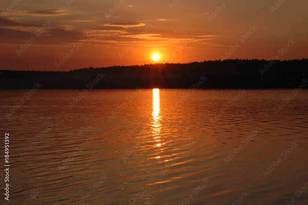 Summer landscape: the lake in the rays of the setting sun.