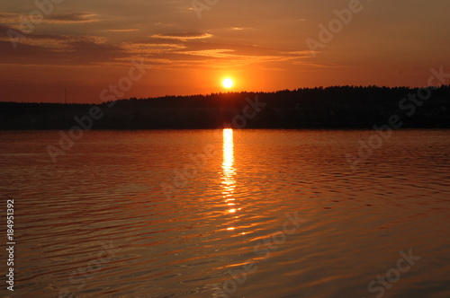Summer landscape: the lake in the rays of the setting sun.