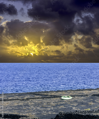 Dramatic sunrise over the ocean before storm with empty boat - Los Cocoteros  Lanzarote  Canary Islands  Spain