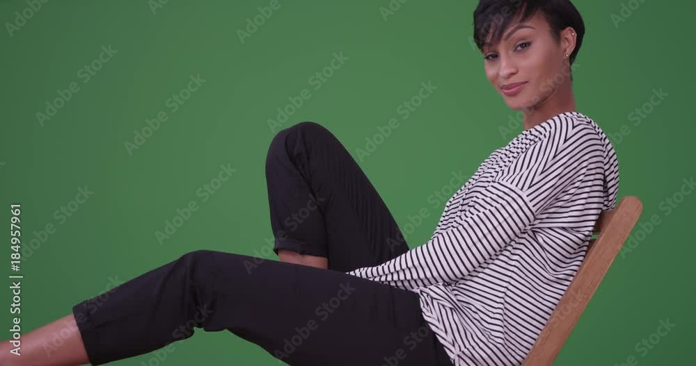 Black woman relaxing on a patio chair while looking at camera on green screen. On green screen to be keyed or composited. Black woman relaxing on a patio chair while looking at camera on green screen. On green screen to be keyed or composited.