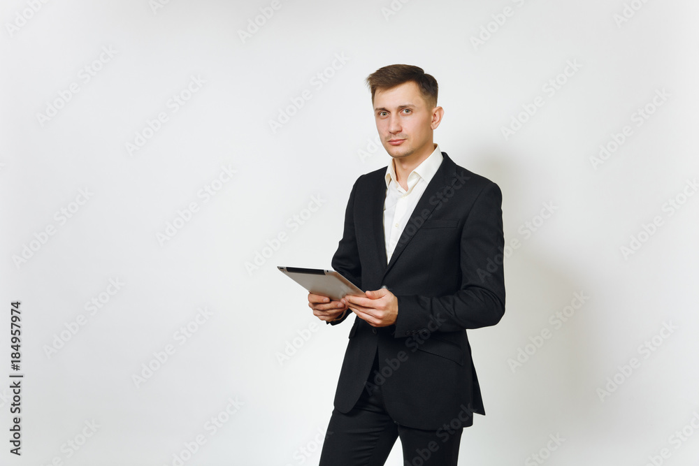 Young successful handsome rich business man in black suit working on modern tablet isolated on white background for advertising. Concept of money, achievement, career and wealth in 25-30 years. Young successful handsome rich business man in black suit working on modern tablet isolated on white background for advertising. Concept of money, achievement, career and wealth in 25-30 years.