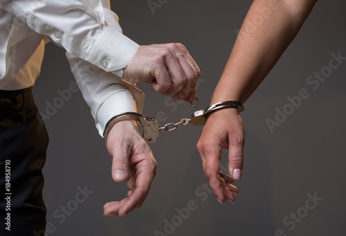 Sending you free. Close up of male hand unlocking female one from joint handcuffs by key. Divorce concept. Isolated