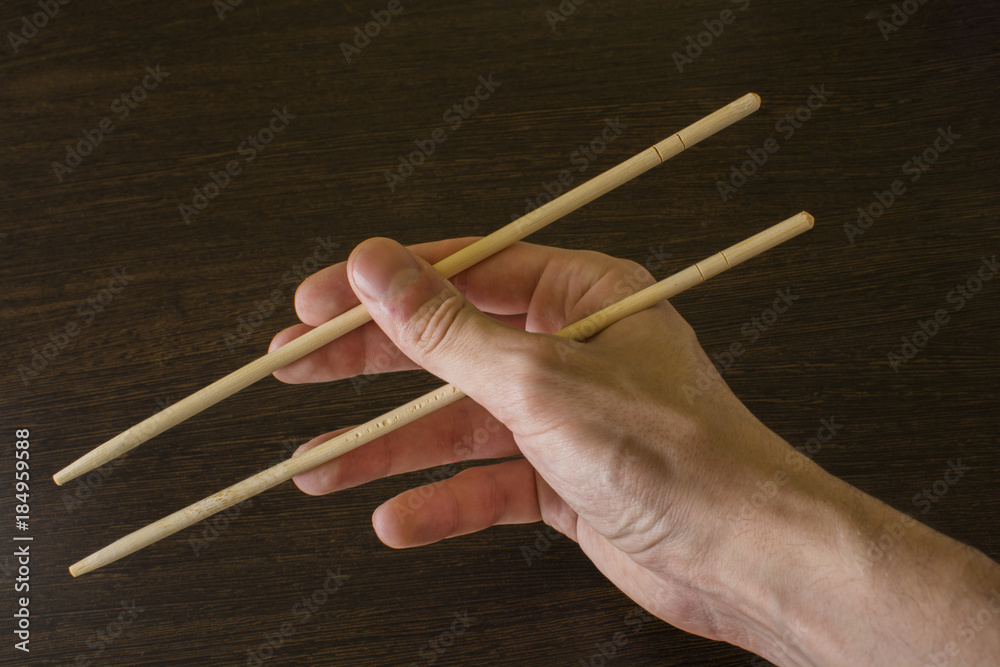 chopsticks in the right hand on the background of wood chopsticks in the right hand on the background of wood
