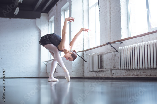 Young ballet dancer bend down in studio active lifestyle