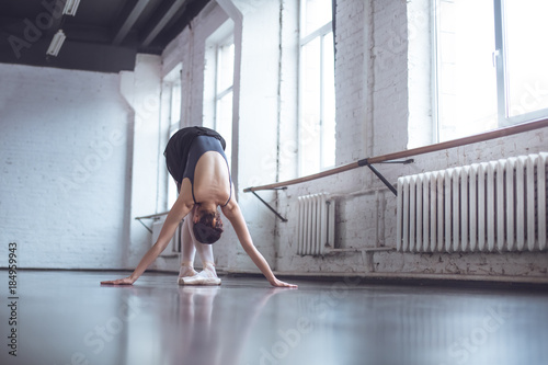 Young ballet dancer bend down in studio active lifestyle