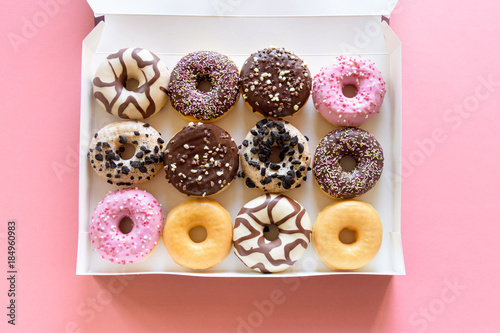 Box of fancy donuts with sprinkles on pink background photo