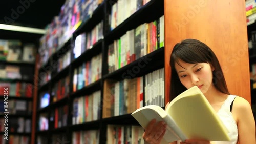 young woman reading book in bookstore