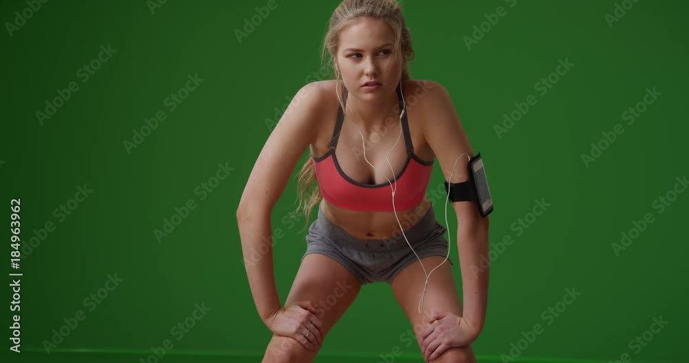 Fit attractive Caucasian woman rests from running on green screen. On green screen to be keyed or composited. Fit attractive Caucasian woman rests from running on green screen. On green screen to be keyed or composited.