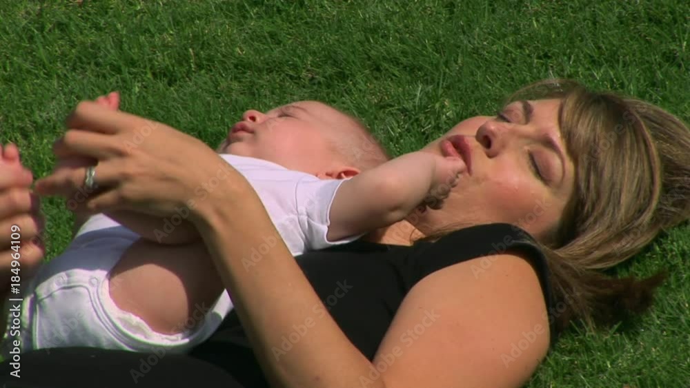 Mother and baby outdoors laying in grass Mother and baby outdoors laying in grass