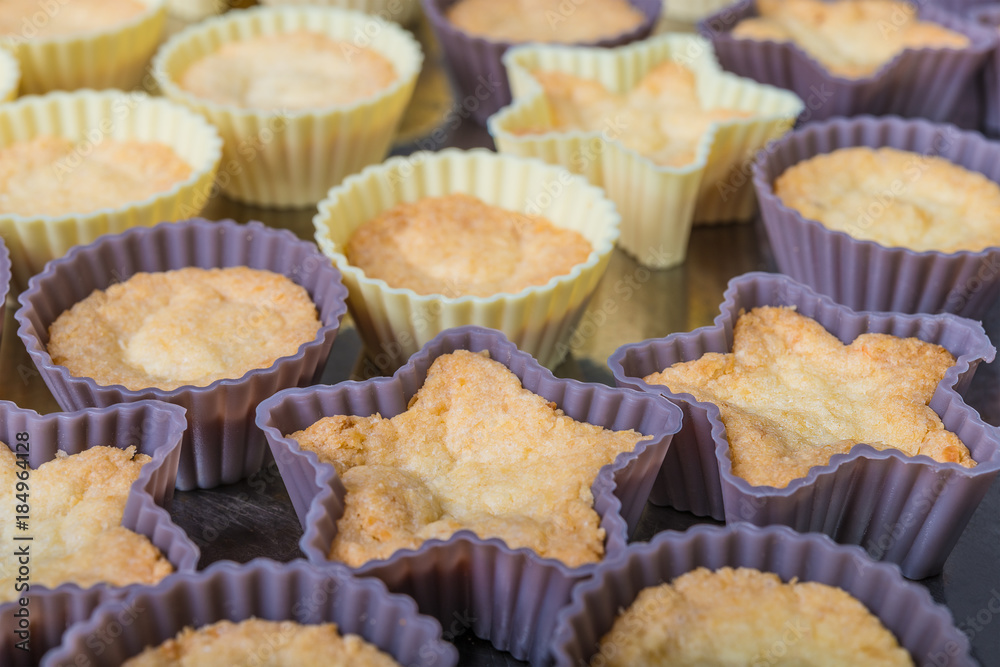 Small cupcakes from sweet coconut pastry as background. Close-up of freshly baked Christmas cookies in decorative silicone molds.