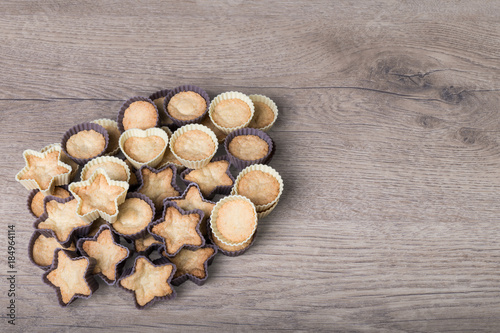 Sweet coconut cupcakes on a wooden background. Heap of freshly baked Christmas pastries in decorative silicone molds.