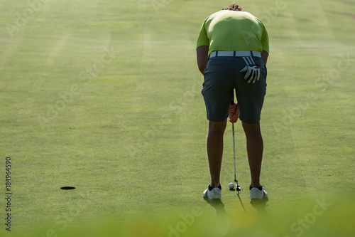 Golfer putting golf ball on the green golf