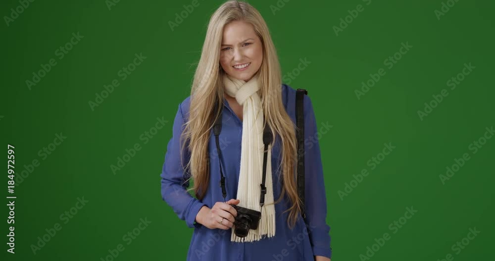 Young female tourist waiting for somebody to take a picture of her with her camera on green screen. On green screen to be keyed or composited. Young female tourist waiting for somebody to take a picture of her with her camera on green screen. On green screen to be keyed or composited.