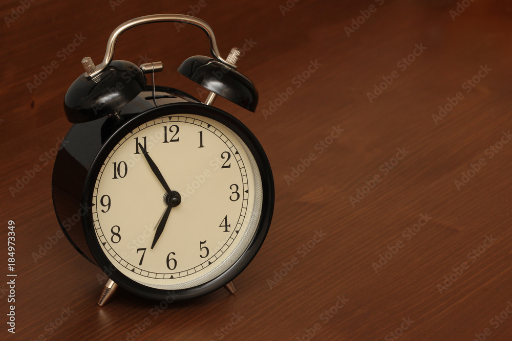 Old fashioned alarm clock on a wood background set to 7 am Old fashioned alarm clock on a wood background set to 7 am