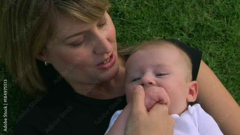 Mother and baby outdoors laying in grass Mother and baby outdoors laying in grass