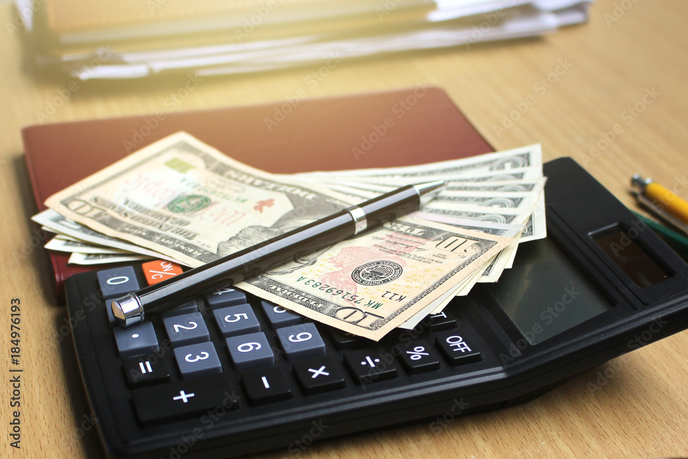 Calculator and dollar money on the office desk investment and property for concept Calculator and dollar money on the office desk investment and property for concept