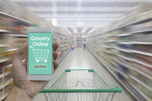 Canvastavla Supermarket aisle with empty shopping cart and Hand use smartphone with grocery